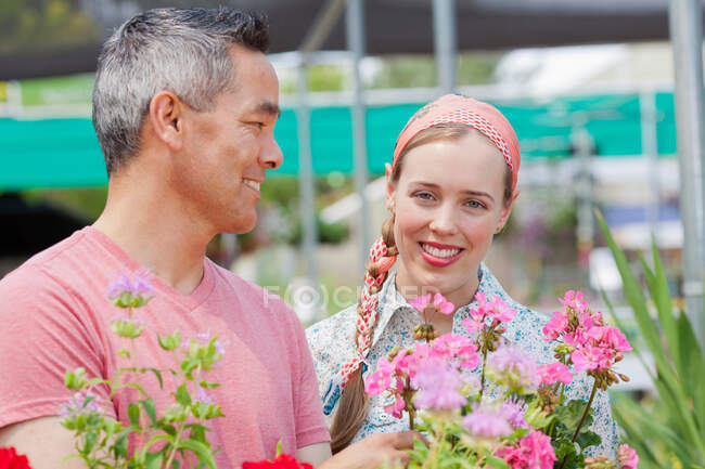 Mature man and mid adult woman shopping in garden centre, smiling — Stock Photo