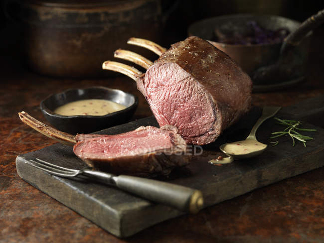 Carved loin of venison on kitchen table with sauce — Stock Photo