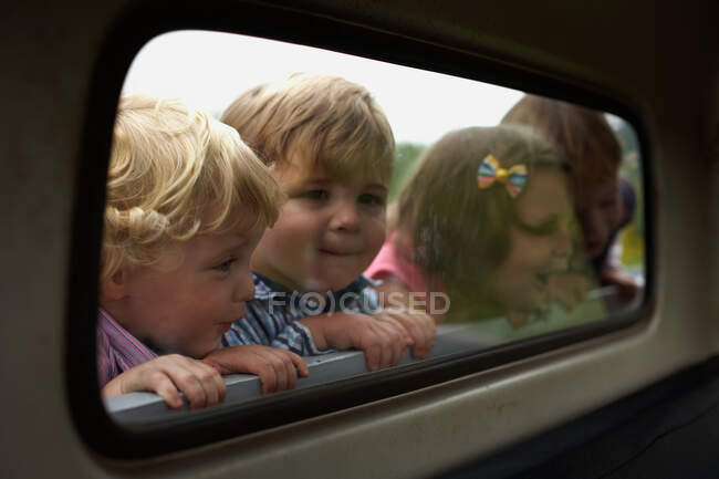 Четверо детей заглядывают в окно грузовика — стоковое фото