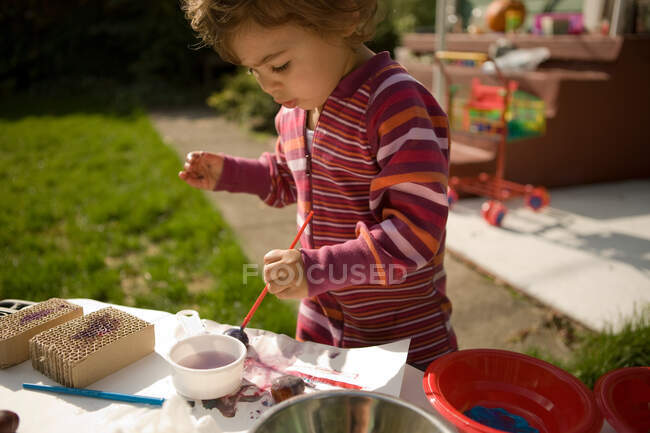 Дівчина Тоддлер грає з фарбами надворі — стокове фото