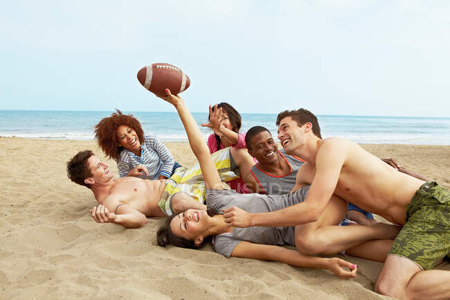 Друзья на пляже играют в футбол — стоковое фото