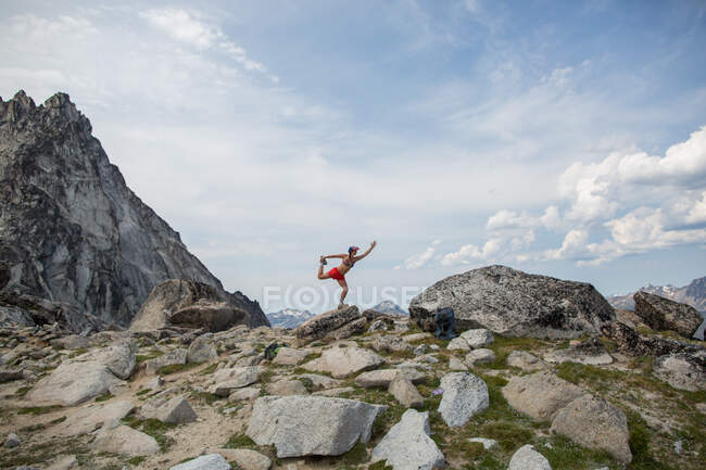 Jovem mulher de pé na rocha, em pose de ioga, Os Encantamentos, Alpine Lakes Wilderness, Washington, EUA — Fotografia de Stock