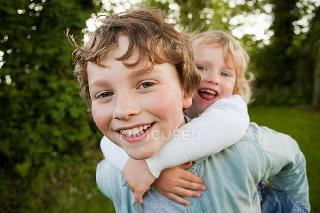 Hermano dando hermana piggyback - foto de stock