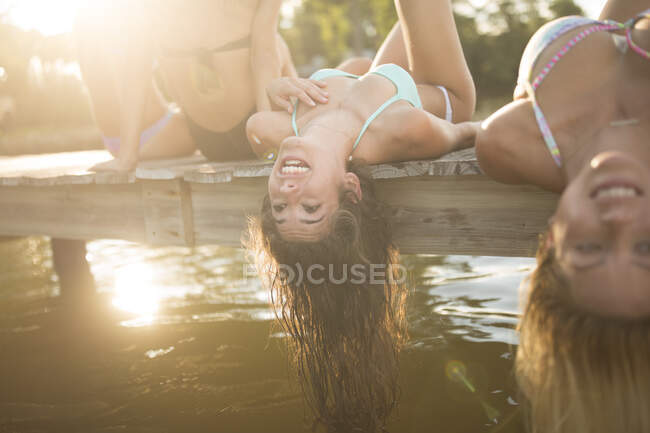 Women lying back on pier dangling long wet hair, Santa Rosa Beach, Florida, USA — Stock Photo