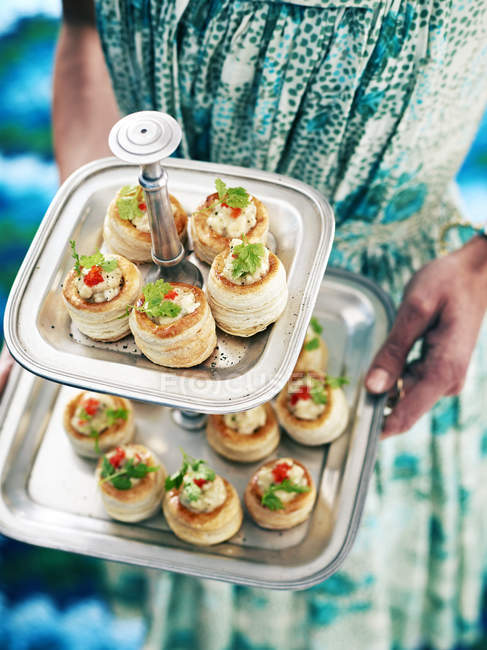 Cropped image of retro styled woman serving vol au vents from cake stand — Stock Photo