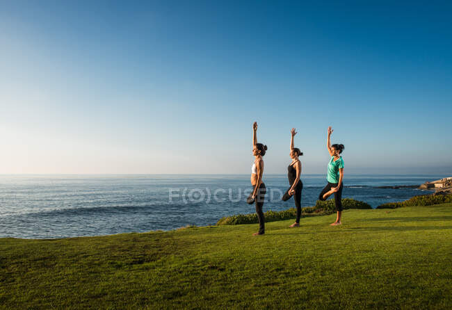 Women on cliff, in yoga positions — Stock Photo