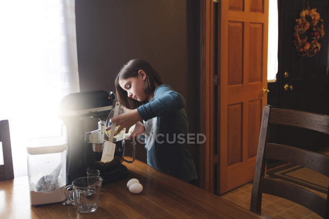 Giovane ragazza versando ingredienti in ciotola di miscelatore di cibo — Foto stock