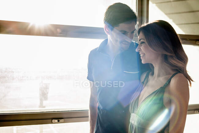 Casal jovem pela janela na luz solar — Fotografia de Stock