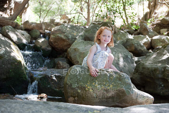 Menina em rochas por rio — Fotografia de Stock