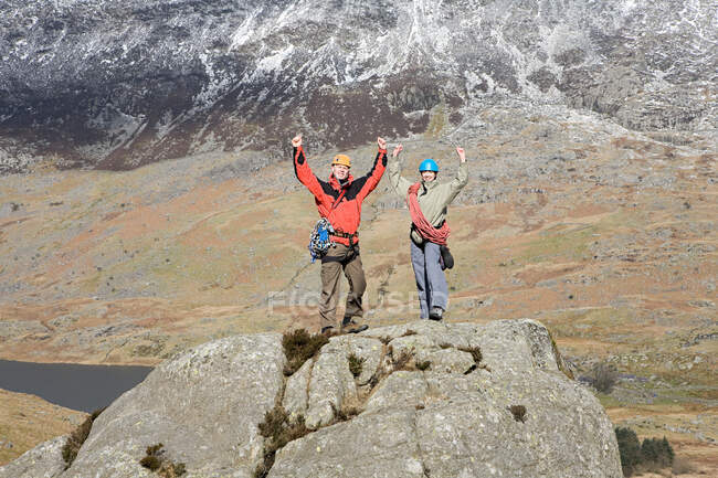 Una pareja con los brazos levantados sobre rocas - foto de stock