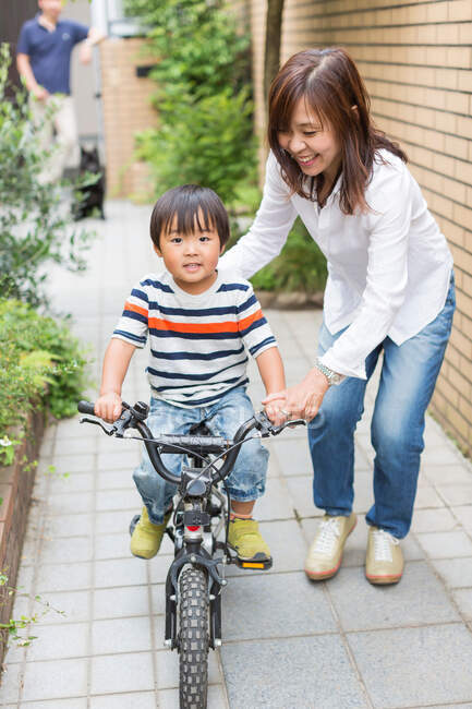 Madre aiutare il figlio ad andare in bicicletta — Foto stock