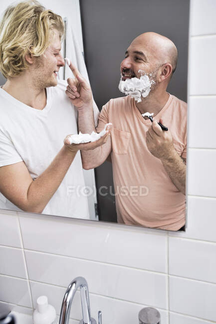 Immagine specchio bagno di coppia maschile scherzare durante la rasatura — Foto stock