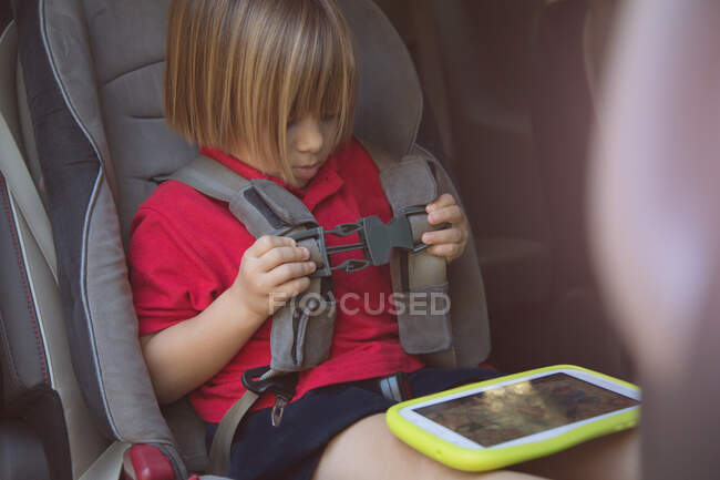 Fille dans le siège de sécurité de voiture attachant sa ceinture de sécurité — Photo de stock