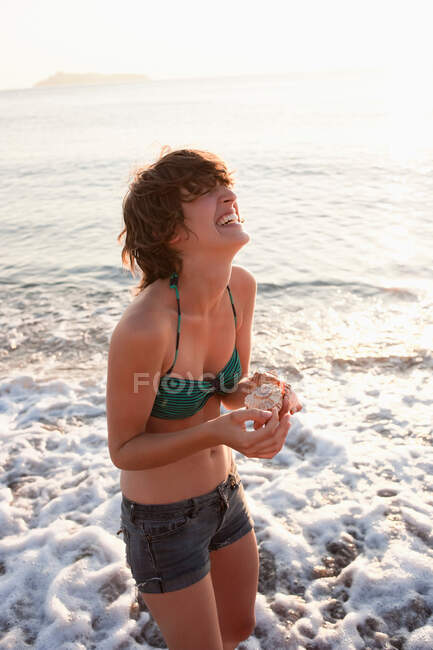Donna che tiene conchiglie sulla spiaggia — Foto stock