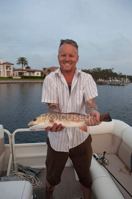 Uomo che detiene catture di pesce in barca — Foto stock