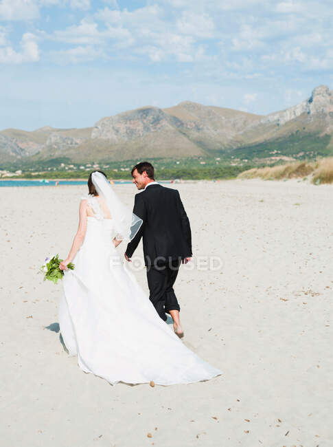 Sposa e sposo a piedi sulla spiaggia — Foto stock