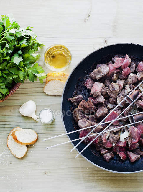 Skewers and meat cooking in pan — Stock Photo