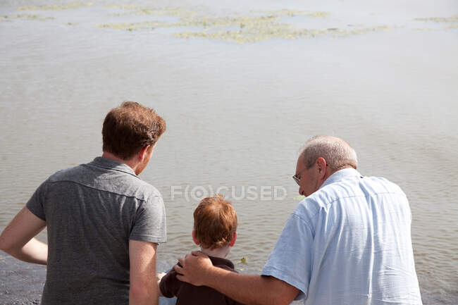 Boy at river with father and grandfather — Stock Photo