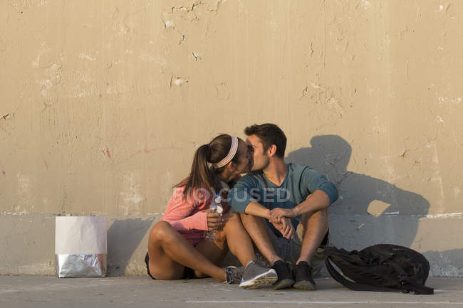 Pareja besándose delante de la pared de hormigón - foto de stock