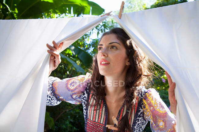 Mulher espreitando através de lençóis — Fotografia de Stock