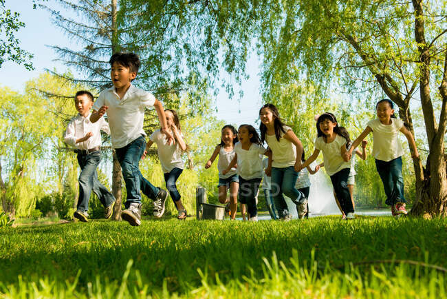 Niños y niñas corriendo en el parque - foto de stock