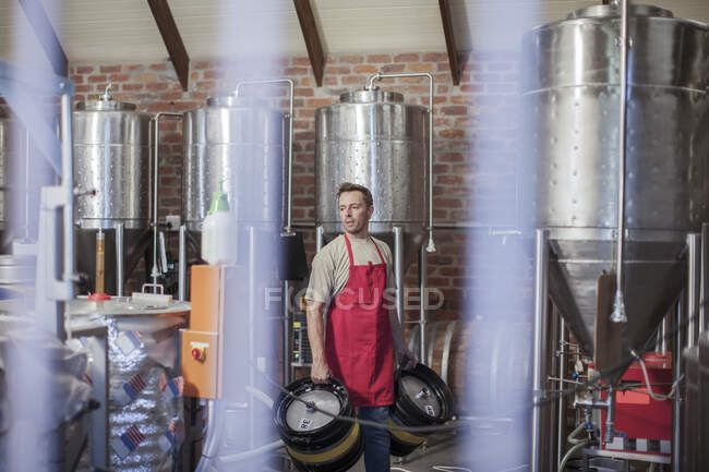 Cape Town, South Africa, young male carrying two beer containers in brewery room — Stock Photo