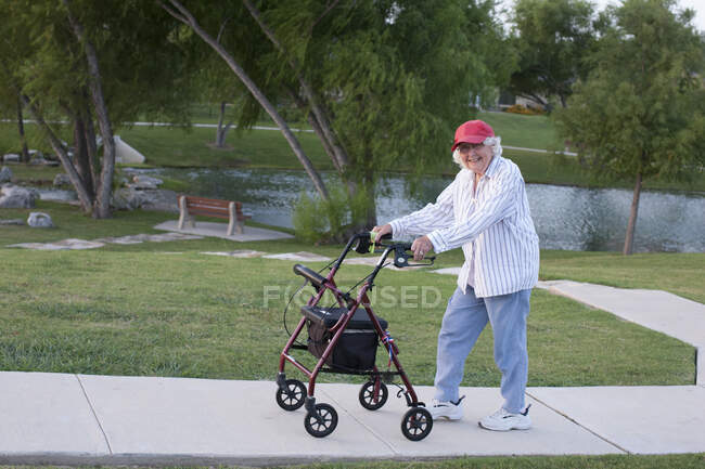 Mulher idosa andando ao ar livre com moldura de caminhada — Fotografia de Stock