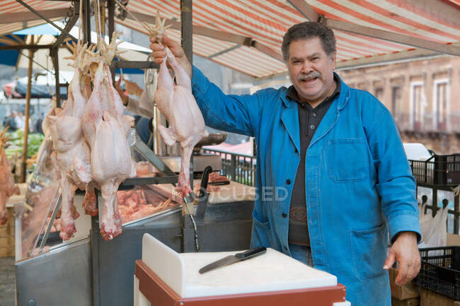 Carnicero en el mercado presentando sus productos - foto de stock
