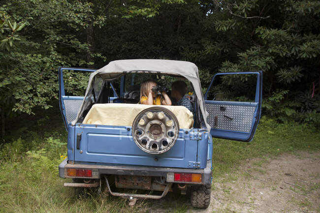 Menina olhando para fora do veículo off-road, usando binóculos — Fotografia de Stock