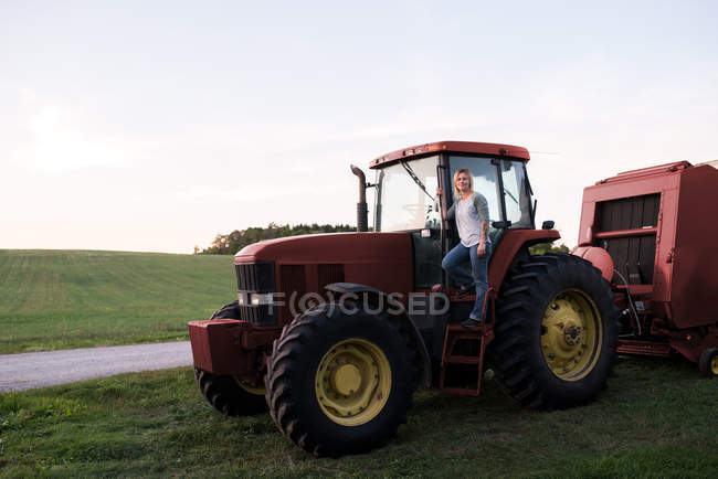 Retrato de la mujer de pie sobre el tractor - foto de stock