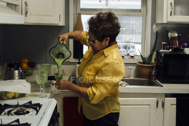 Mulher derramando smoothie na cozinha — Fotografia de Stock