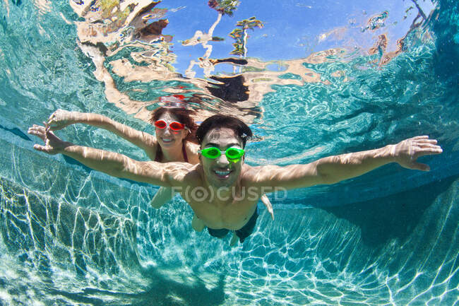 Молодая пара плавает под водой в бассейне — стоковое фото