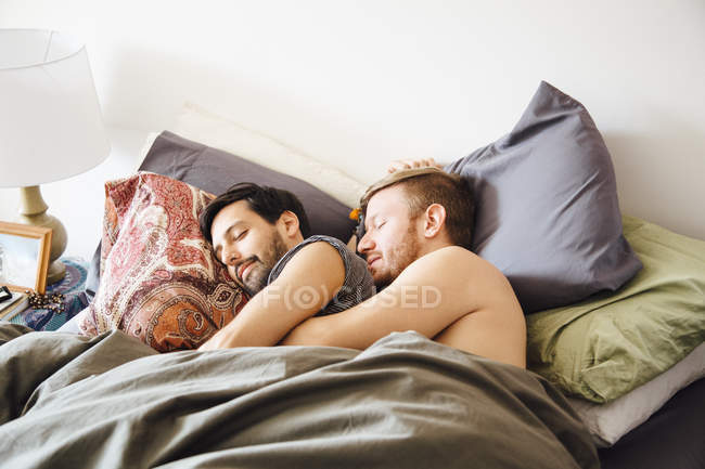 Male couple in bed, hugging whilst sleeping — Stock Photo