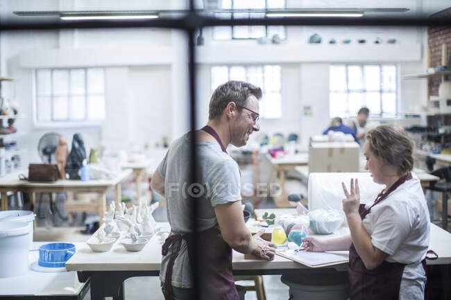 Ciudad del Cabo, Sudáfrica, joven varón discutiendo con su compañero de trabajo en taller de cerámica - foto de stock
