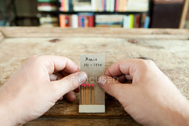 Person im Besitz eines Streichholzbuchs mit darauf geschriebener Telefonnummer — Stockfoto