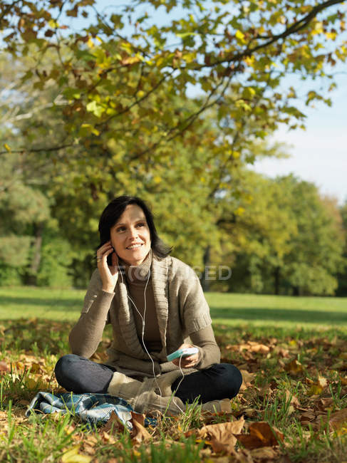 Woman under tree listening to music — Stock Photo