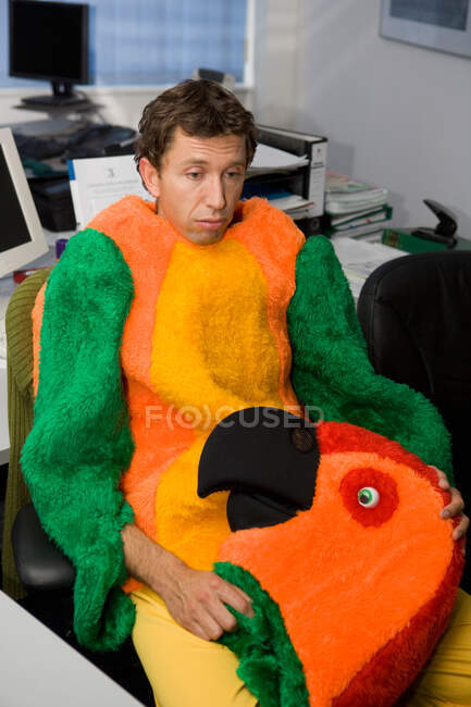 Человек в офисе, одетый в костюм попугая — стоковое фото
