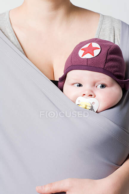 Un bebé en una honda de bebé - foto de stock