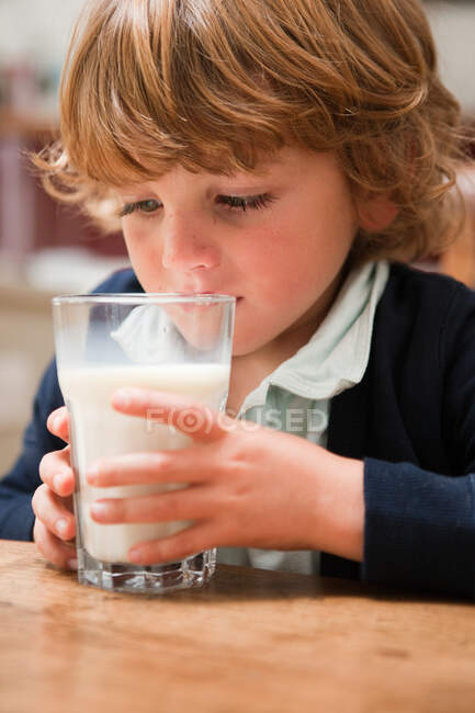 Jeune garçon buvant un grand verre de lait — Photo de stock