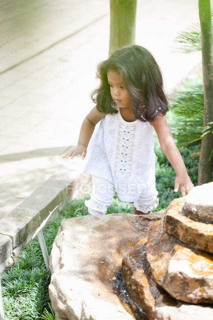 Fille escalade sur la fontaine de pierre — Photo de stock