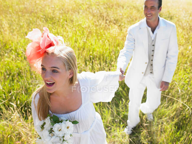 Pareja casada caminando en un campo - foto de stock