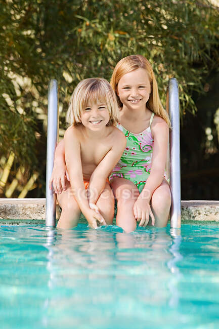 Brother and sister by swimming pool — Stock Photo