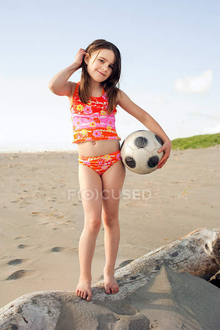 Fille tenant ballon de football à la plage — Photo de stock
