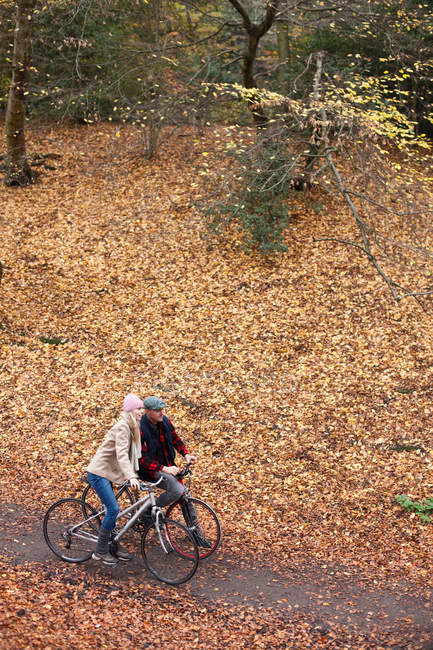 Пара катання на велосипеді по шляху через листя — стокове фото