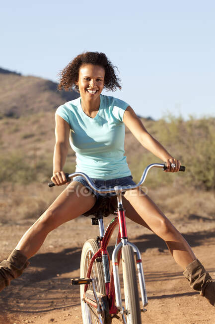 Portrait of young woman cycling downhill in desert — Stock Photo