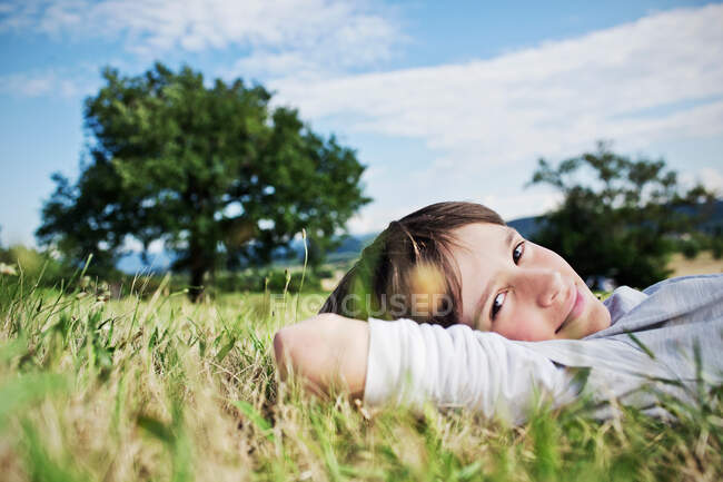 Улыбающийся мальчик, лежащий в траве — стоковое фото