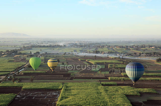 Hot air balloons over fields — Stock Photo