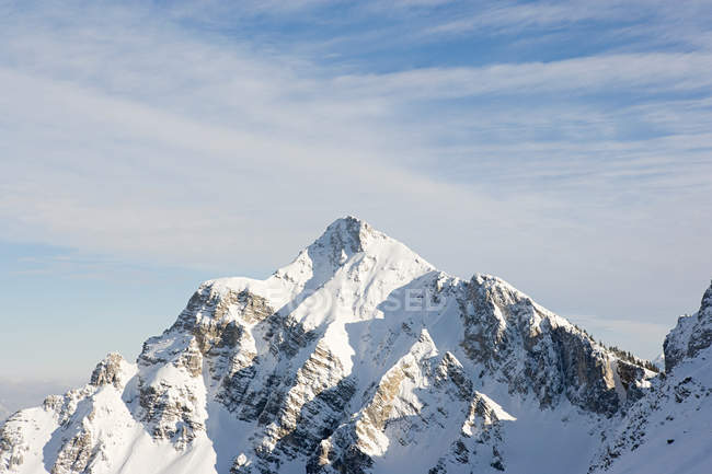 Pico de montanha coberto de neve em luz solar brilhante — Fotografia de Stock