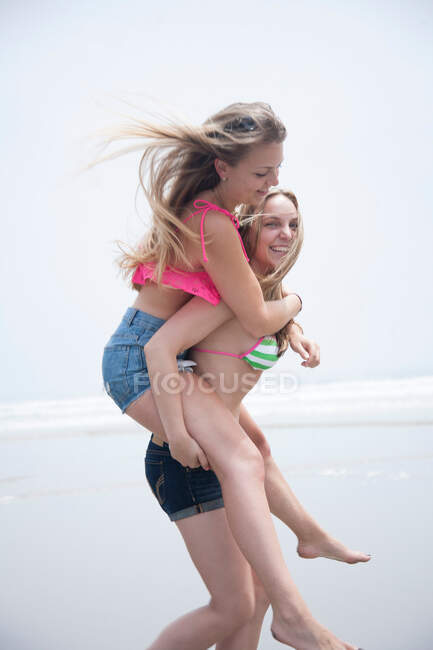 Junge Frau huckepack am Strand — Stockfoto