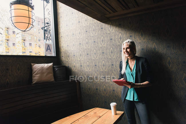 Mulher usando tablet digital e sorrindo no café — Fotografia de Stock